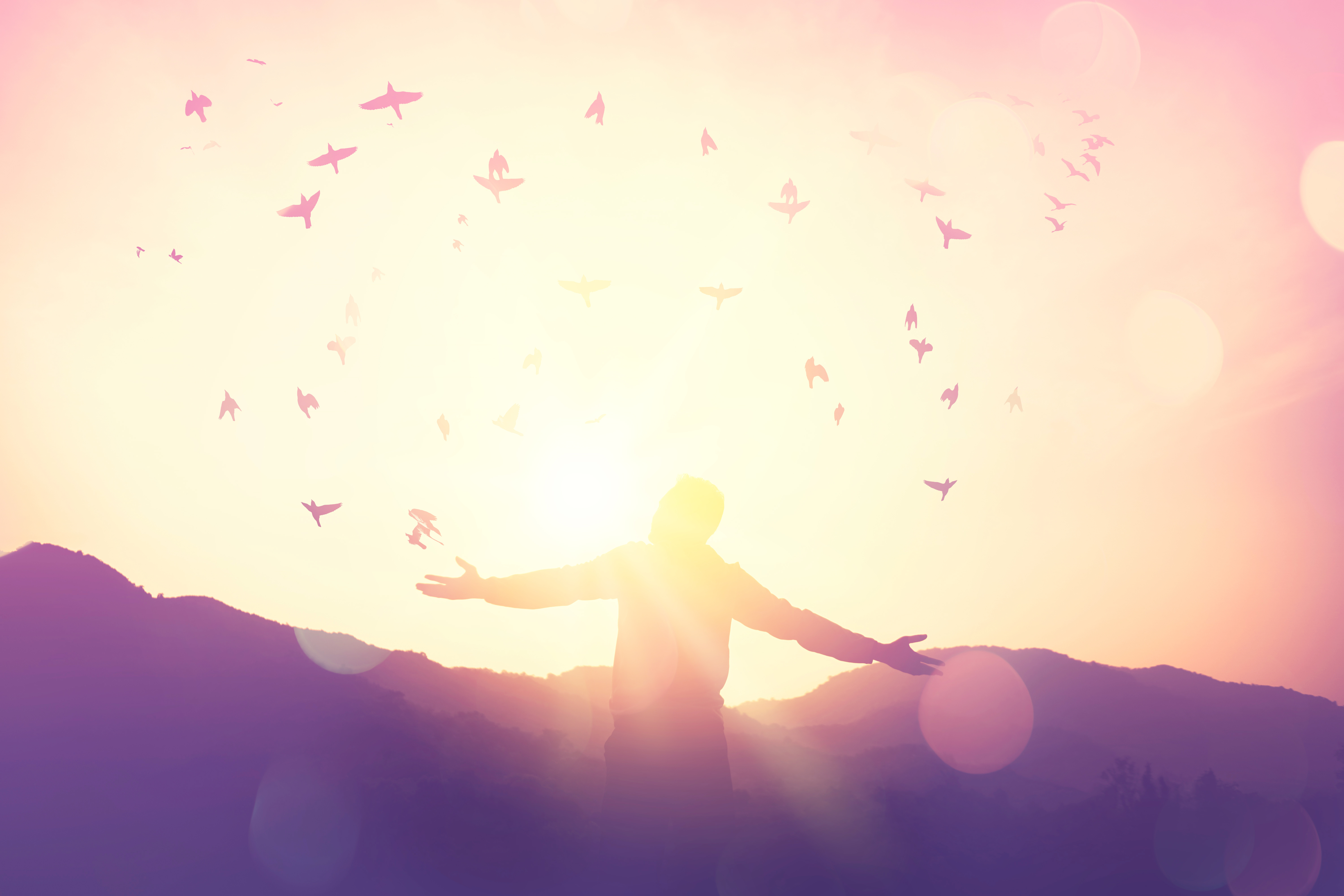 Person with outstretched arms at sunrise, symbolizing peace and transformation through meditation